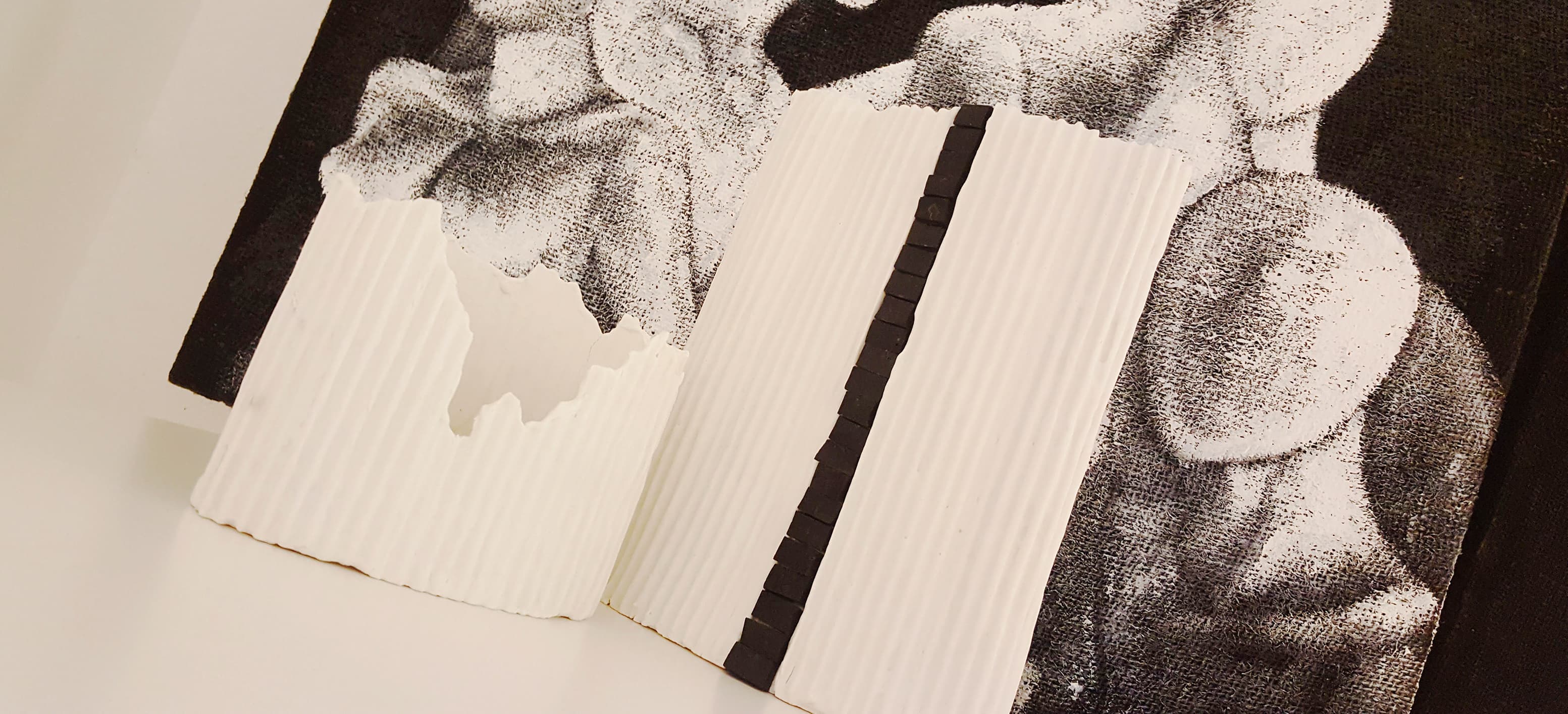 vasi in porcellana paperclay bianca, motivo a losanghe amientata con sfondo quadro moderno bianco e nero manichini